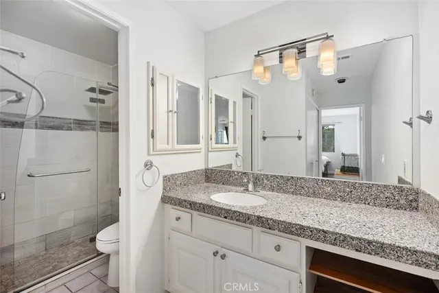 a bathroom with a granite countertop sink toilet and shower