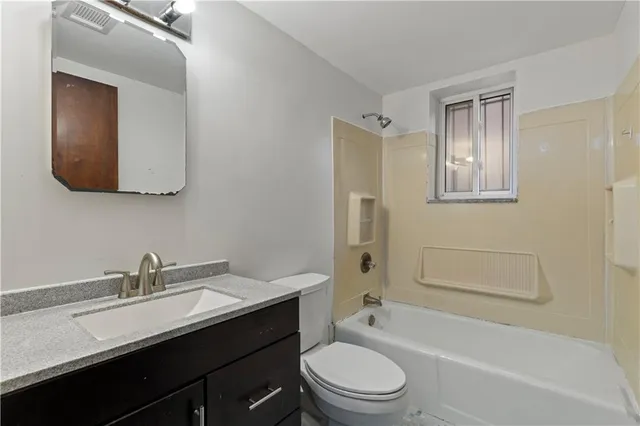 a bathroom with a toilet a sink a mirror a bathtub and vanity