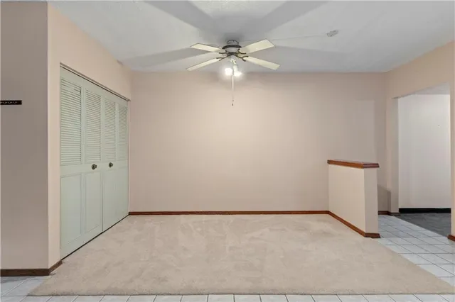 an empty room with a ceiling fan and carpet