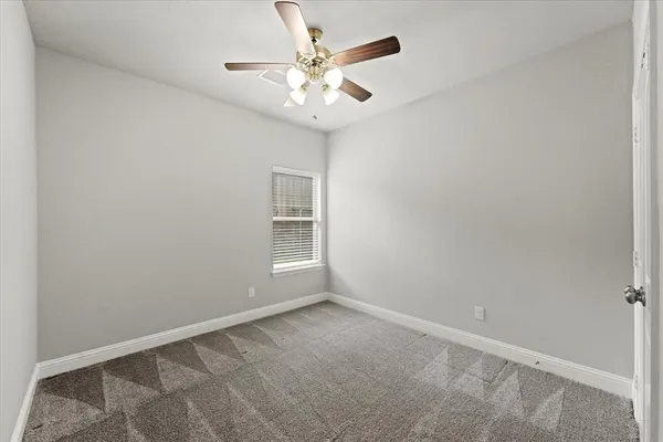 an empty room with a chandelier fan and windows