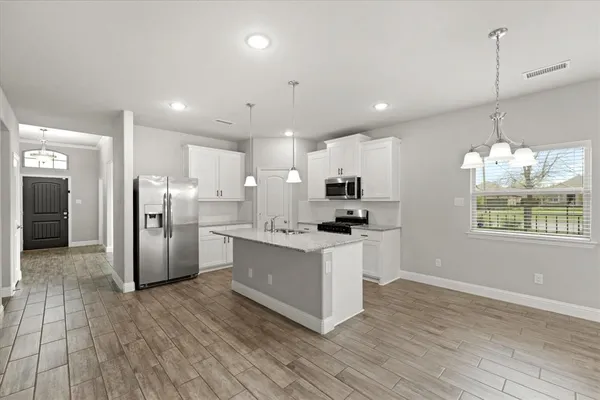a kitchen with stainless steel appliances kitchen island hardwood floor sink stove and wooden cabinets