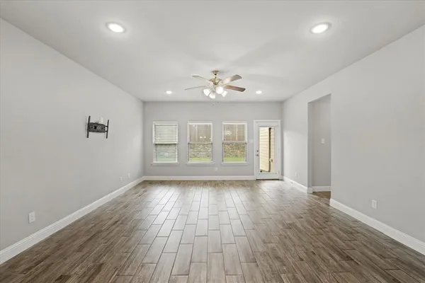 a view of an empty room with a window and wooden floor