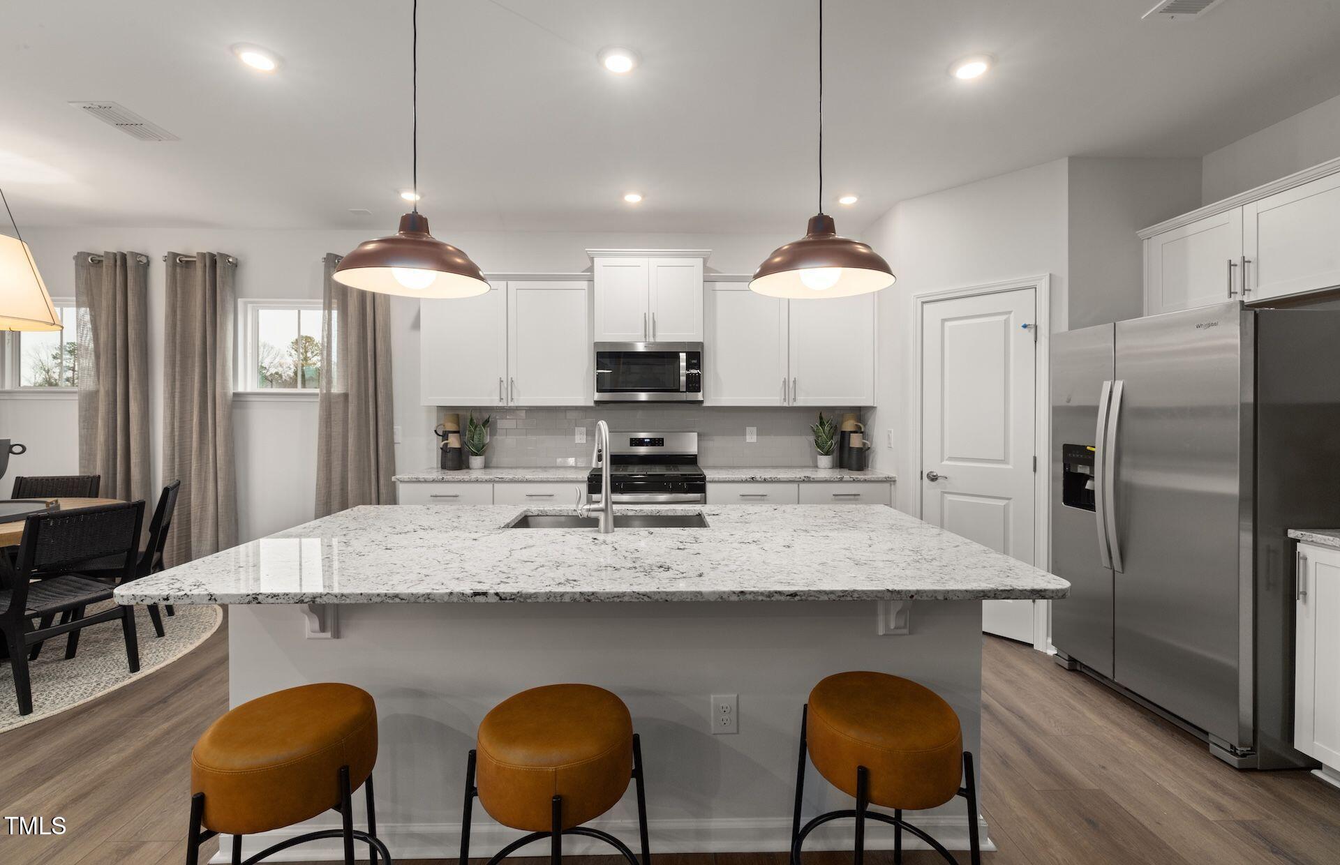 1003 Freestone Road Durham, NC 27703 - Photo 2 of 20 a kitchen with stainless steel appliances granite countertop a sink a stove a refrigerator a dining table and chairs with wooden floor