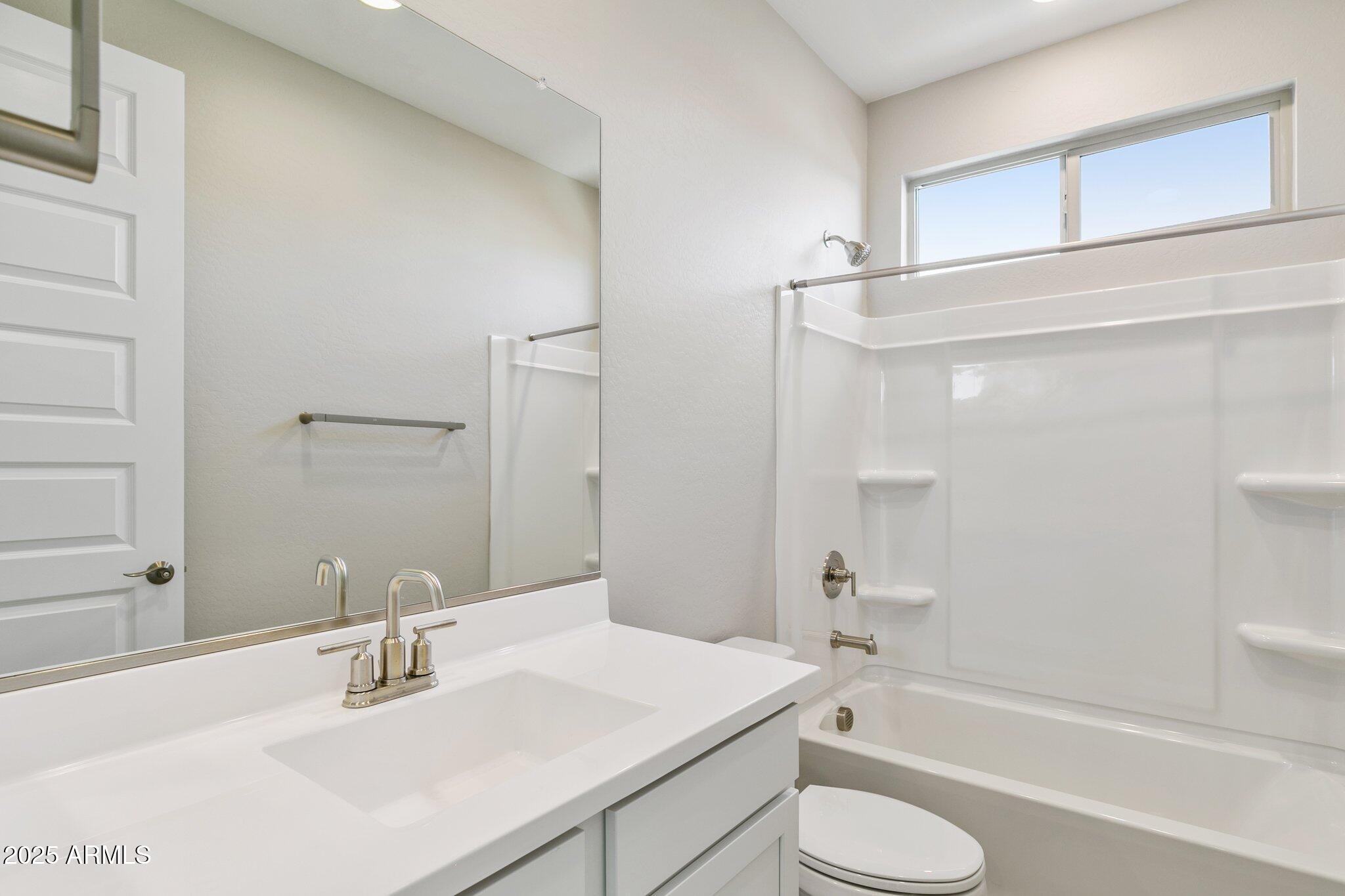 14742 West Soft Wind Drive Surprise, AZ 85387 - Photo 16 of 26 a bathroom with a sink toilet vanity and shower