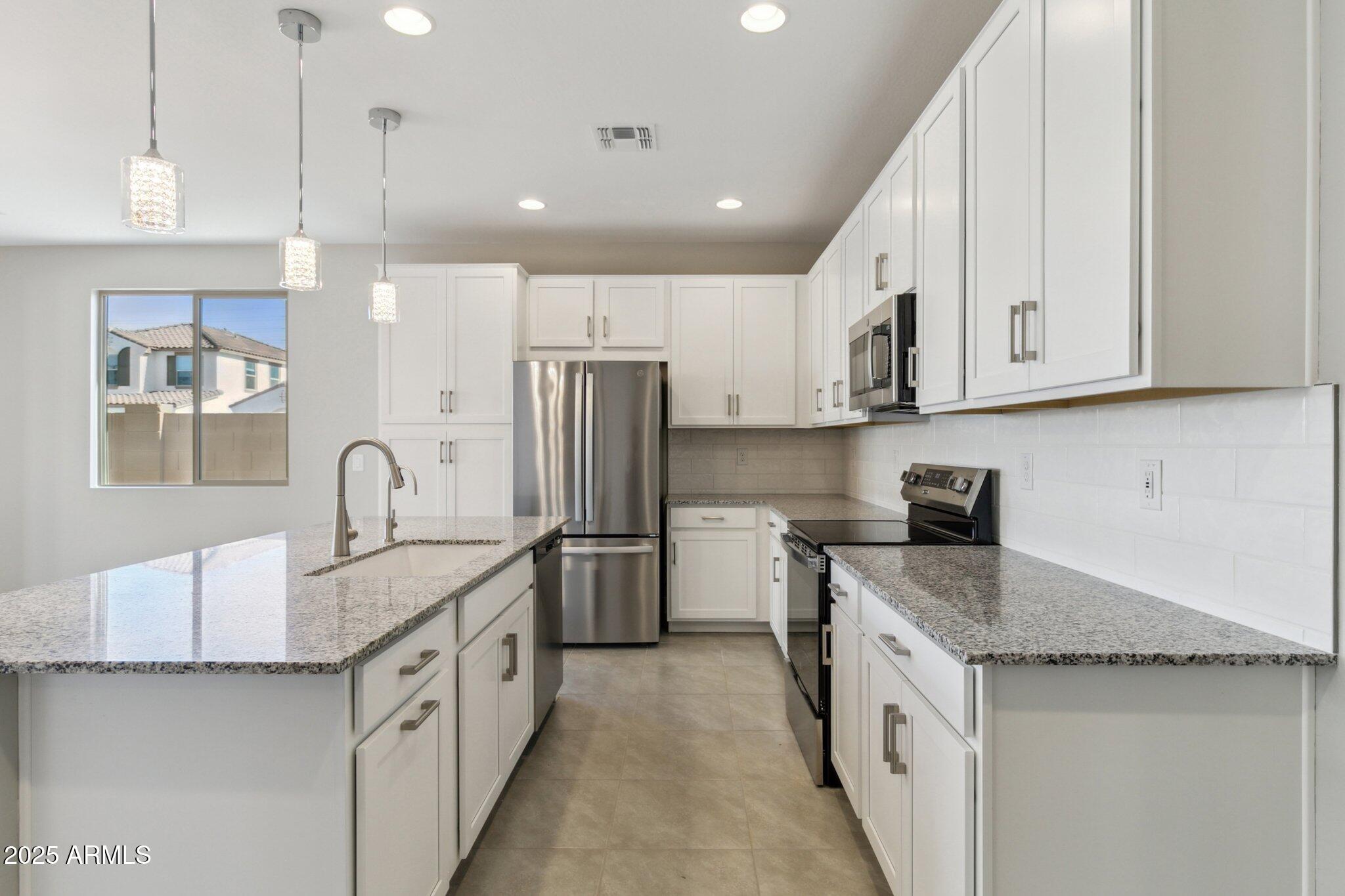 14742 West Soft Wind Drive Surprise, AZ 85387 - Photo 5 of 26 a kitchen with stainless steel appliances granite countertop a sink stove and refrigerator