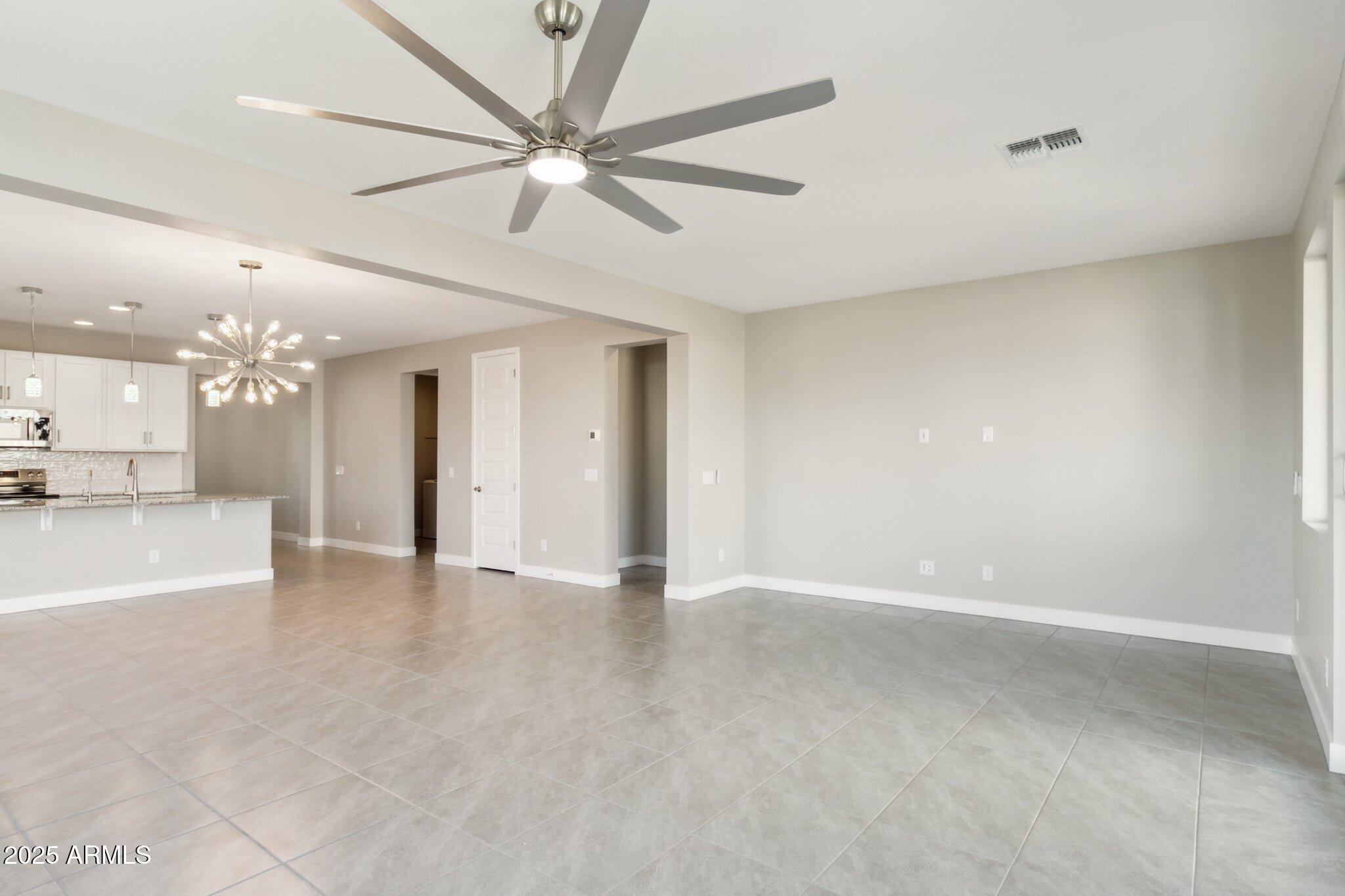 14742 West Soft Wind Drive Surprise, AZ 85387 - Photo 7 of 26 an empty room with a kitchen and a chandelier fan
