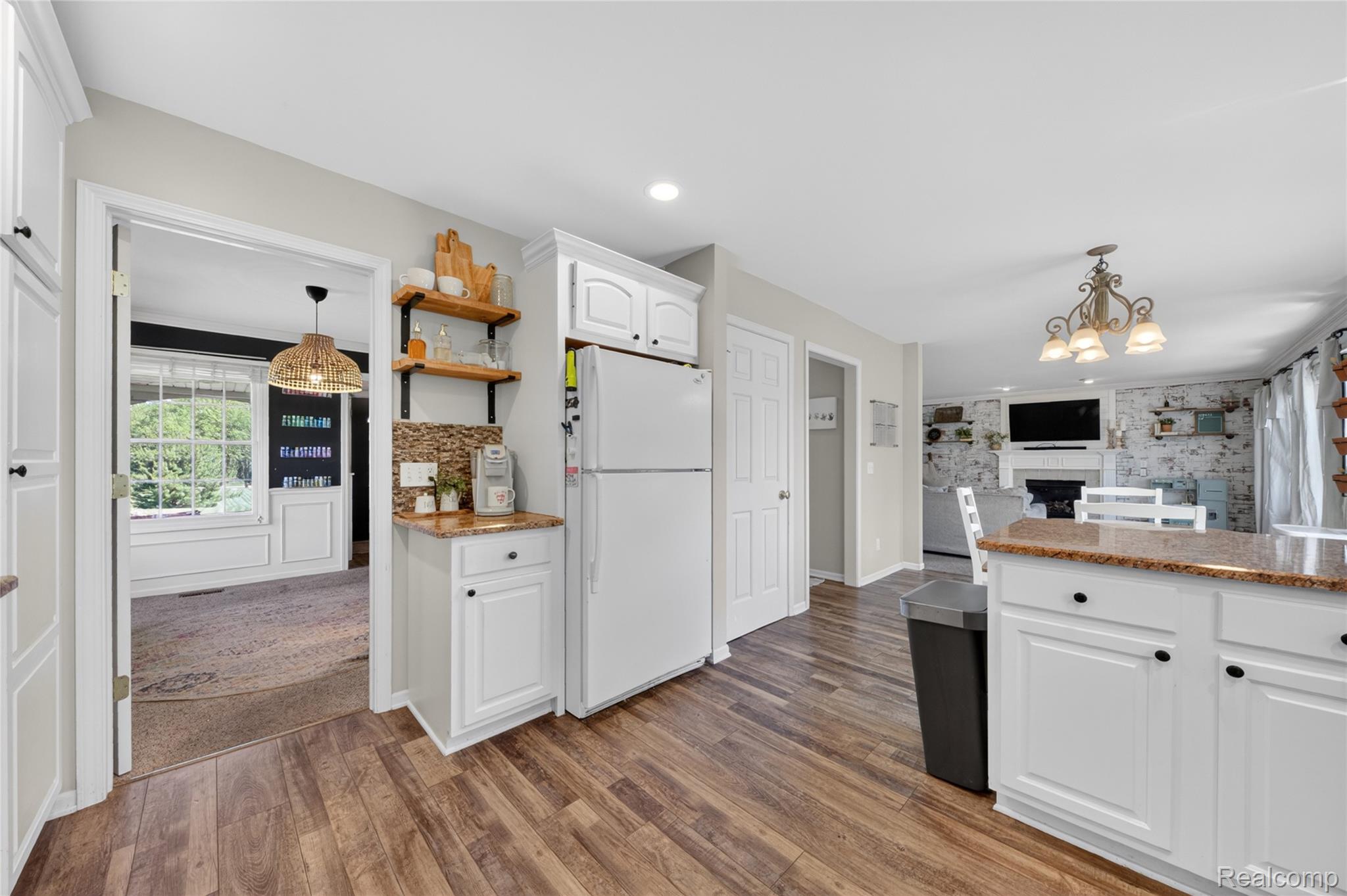 9191 Judd Road Fowlerville, MI 48836 - Photo 12 of 74 Kitchen featuring wood-finish flooring, white cabinetry, granite countertops, and a mosaic tile backsplash