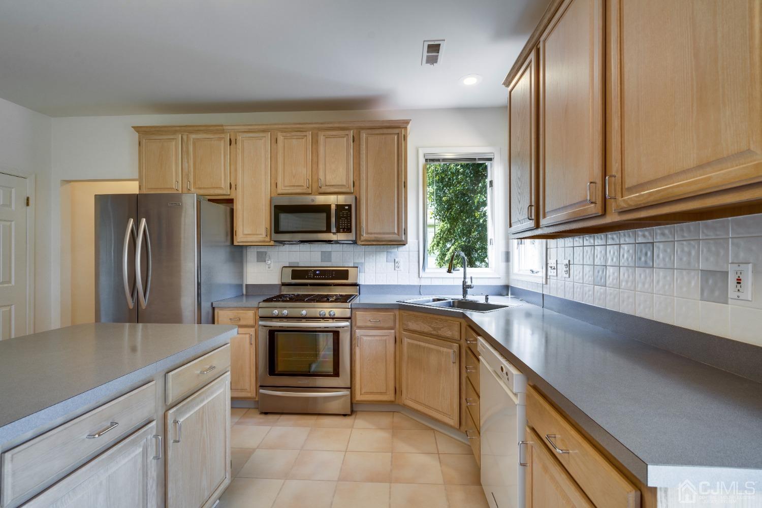 9 Dickinson Road Kendall Park, NJ 08824 - Photo 11 of 34 a kitchen with a sink stainless steel appliances and cabinets