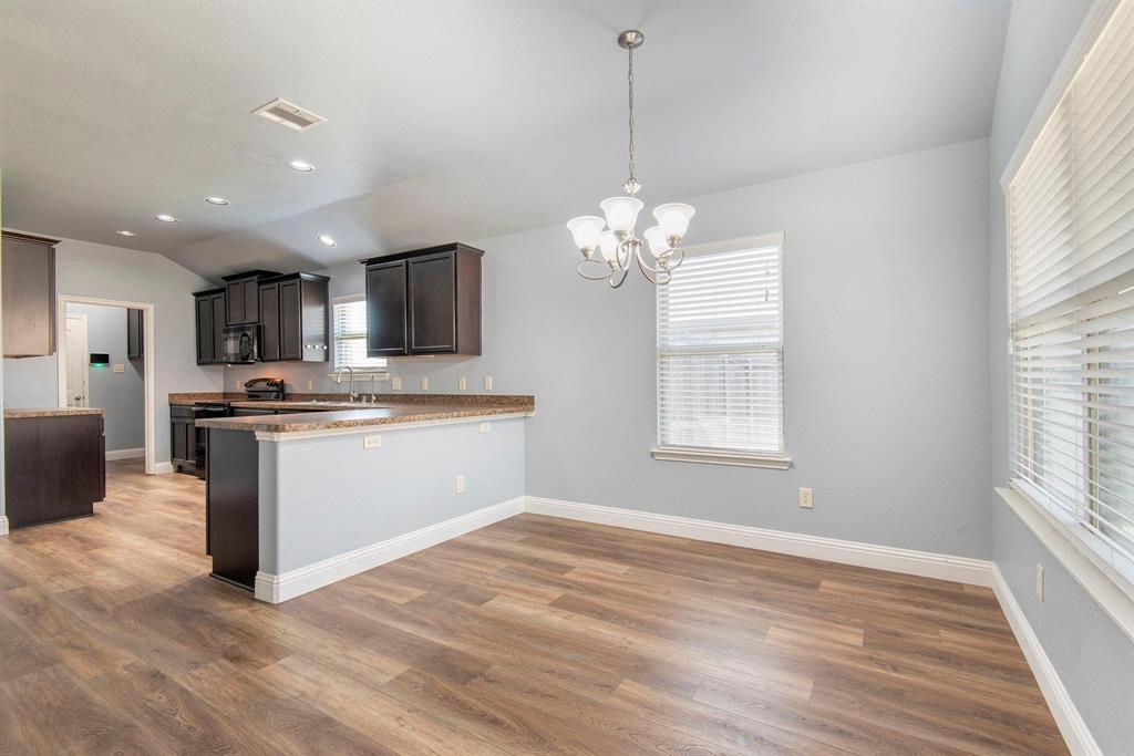 1813 Rodeo Drive Anna, TX 75409 - Photo 2 of 6 Kitchen with a chandelier, a peninsula, pendant lighting, dark wood finished floors, and lofted ceiling