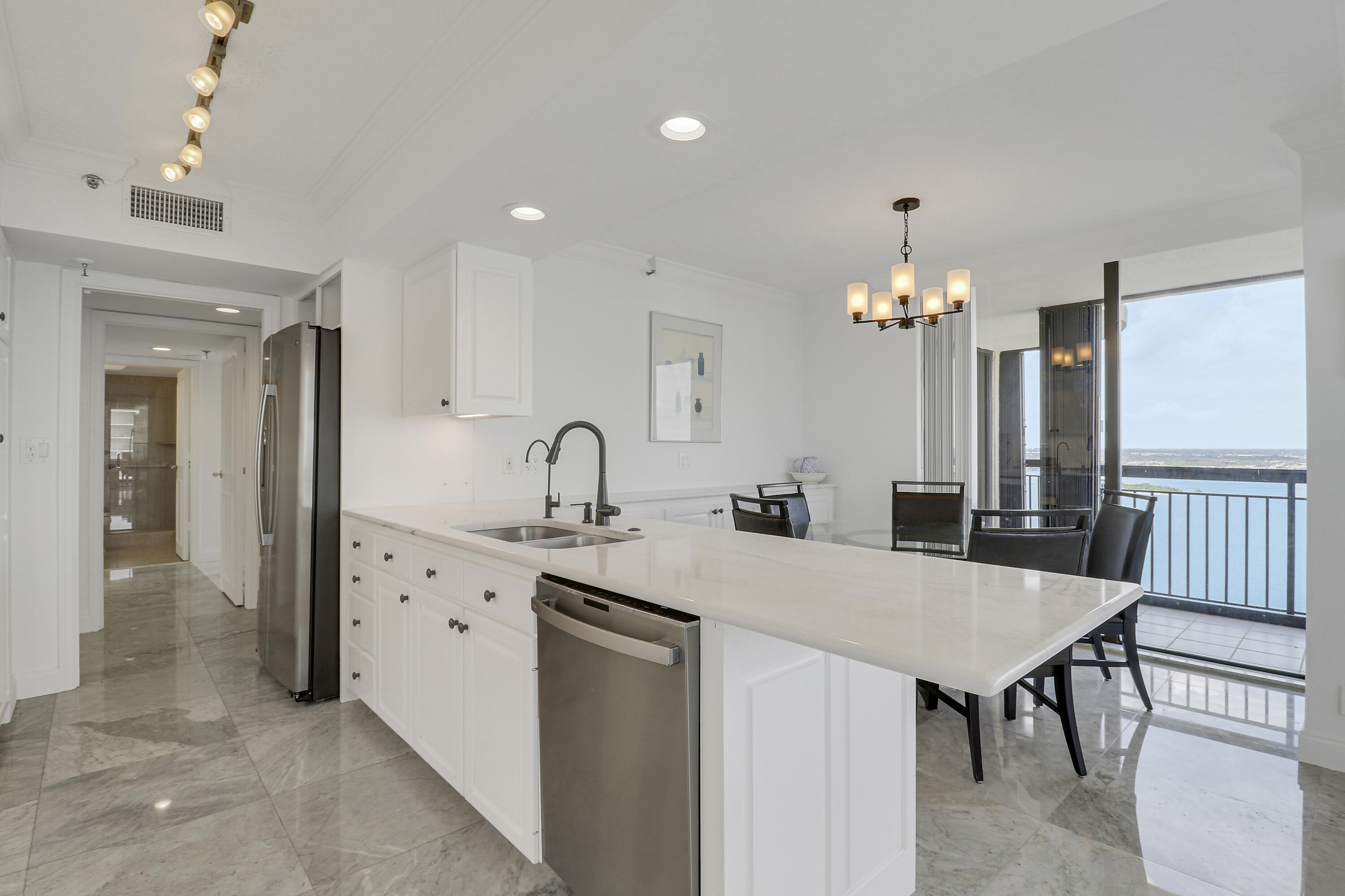 5380 North Ocean Drive, Unit 22J Riviera Beach, FL 33404 - Photo 19 of 53 a kitchen with granite countertop a table chairs sink and refrigerator