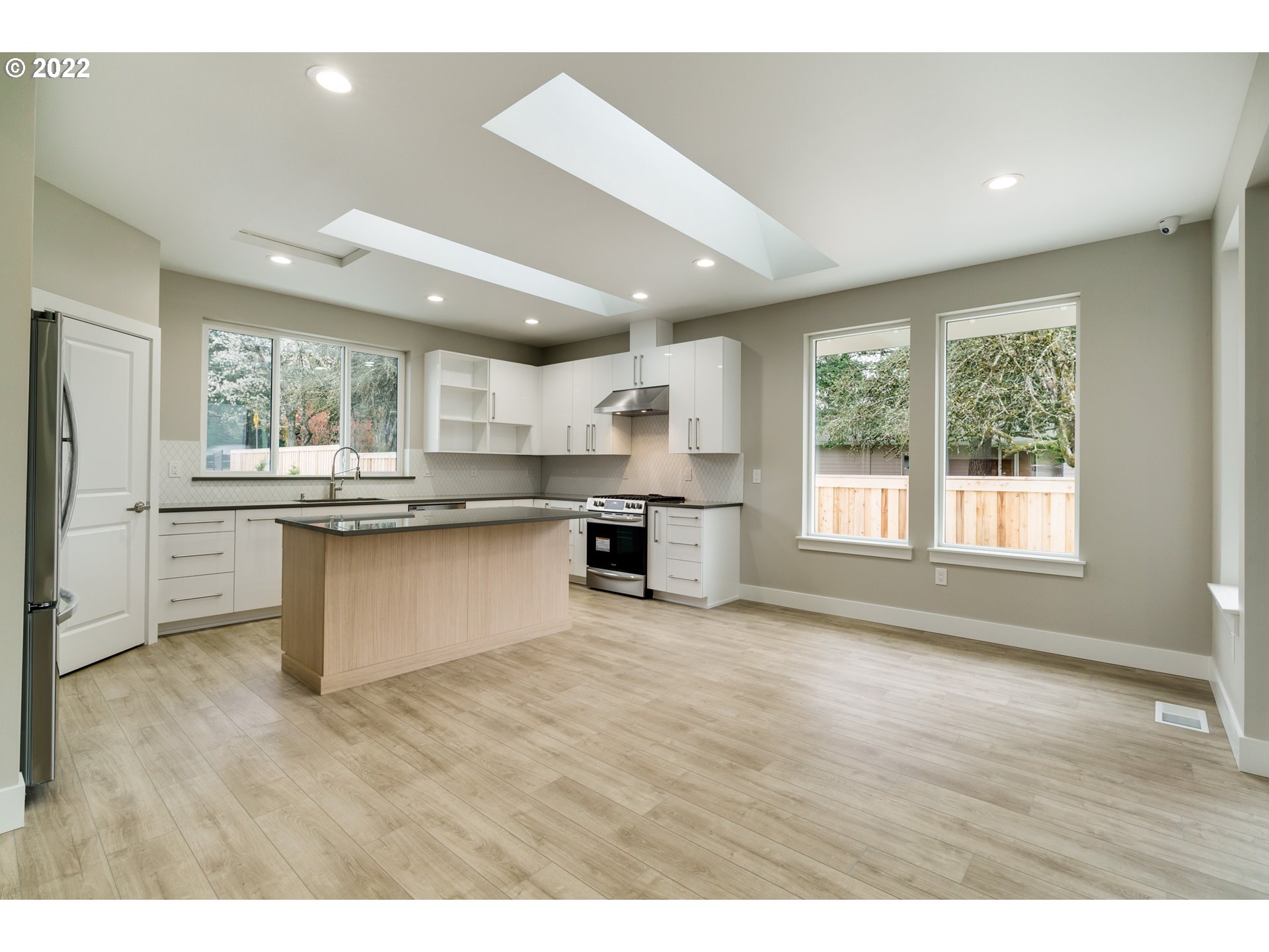 7975 Southwest Oleson Road Portland, OR 97223 - Photo 8 of 32 a kitchen with stainless steel appliances granite countertop a large window a wooden floor and a sink