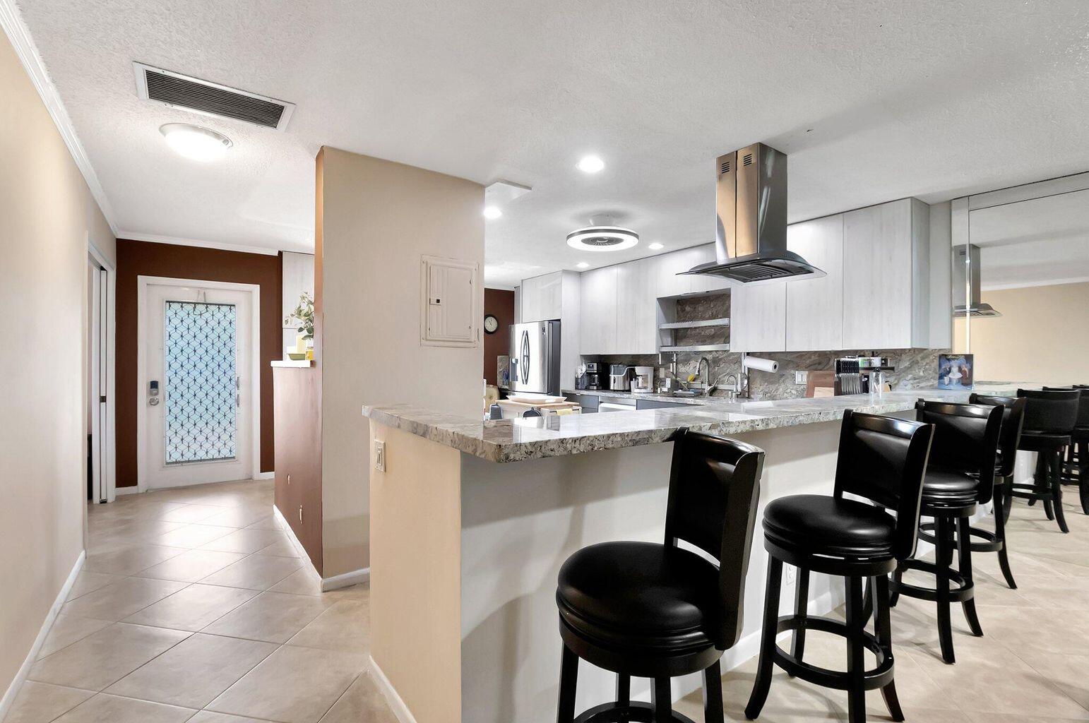 1710 Northwest 18th Avenue, Unit 204 Delray Beach, FL 33445 - Photo 6 of 21 a kitchen with cabinets a sink and chairs
