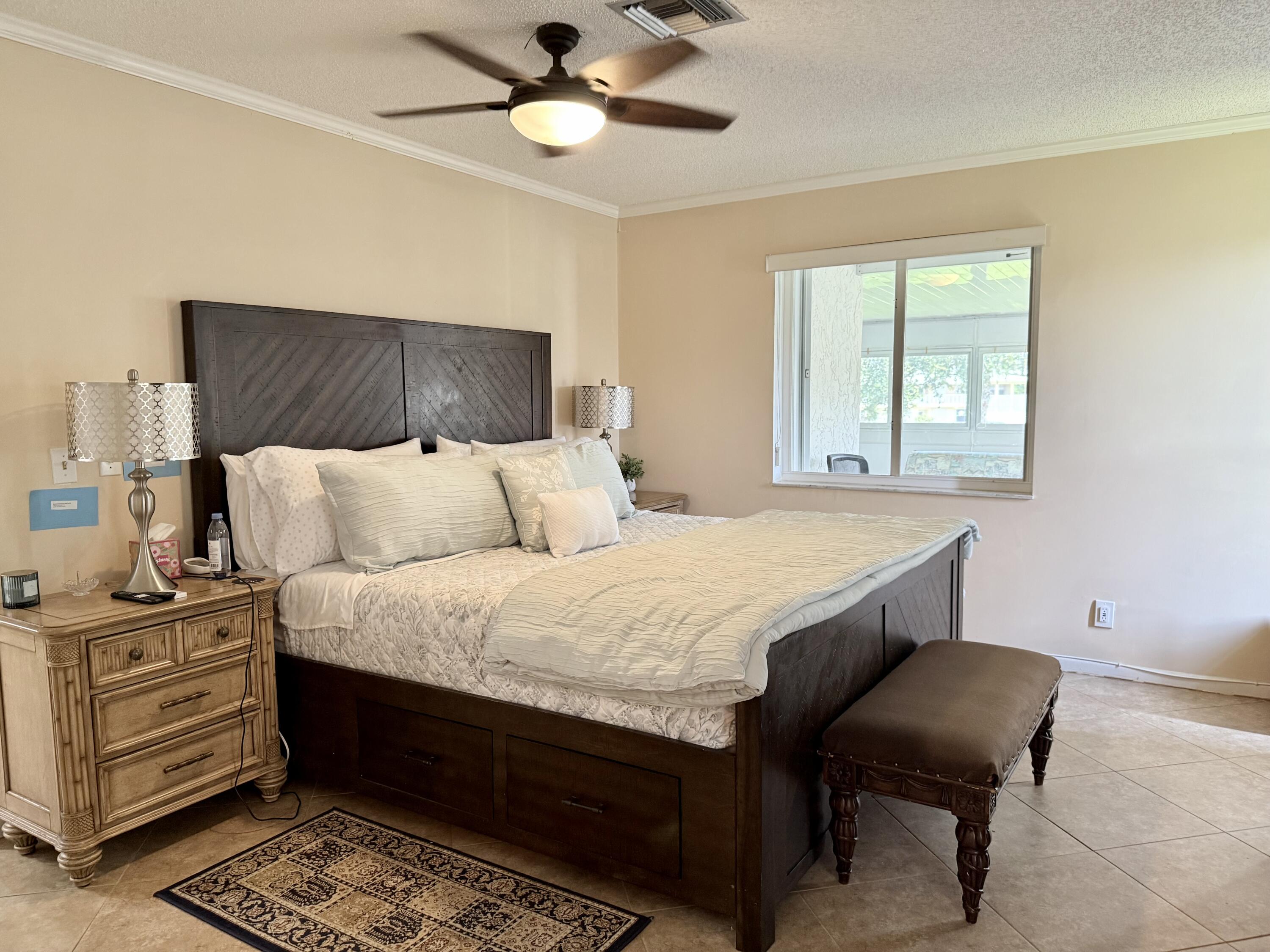 1710 Northwest 18th Avenue, Unit 204 Delray Beach, FL 33445 - Photo 10 of 21 a bedroom with a bed and a chandelier