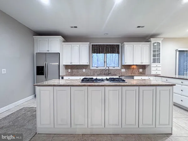 a large kitchen with granite countertop a sink and white cabinets