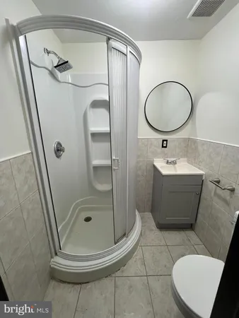 a bathroom with a sink a mirror a toilet and a glass door shower
