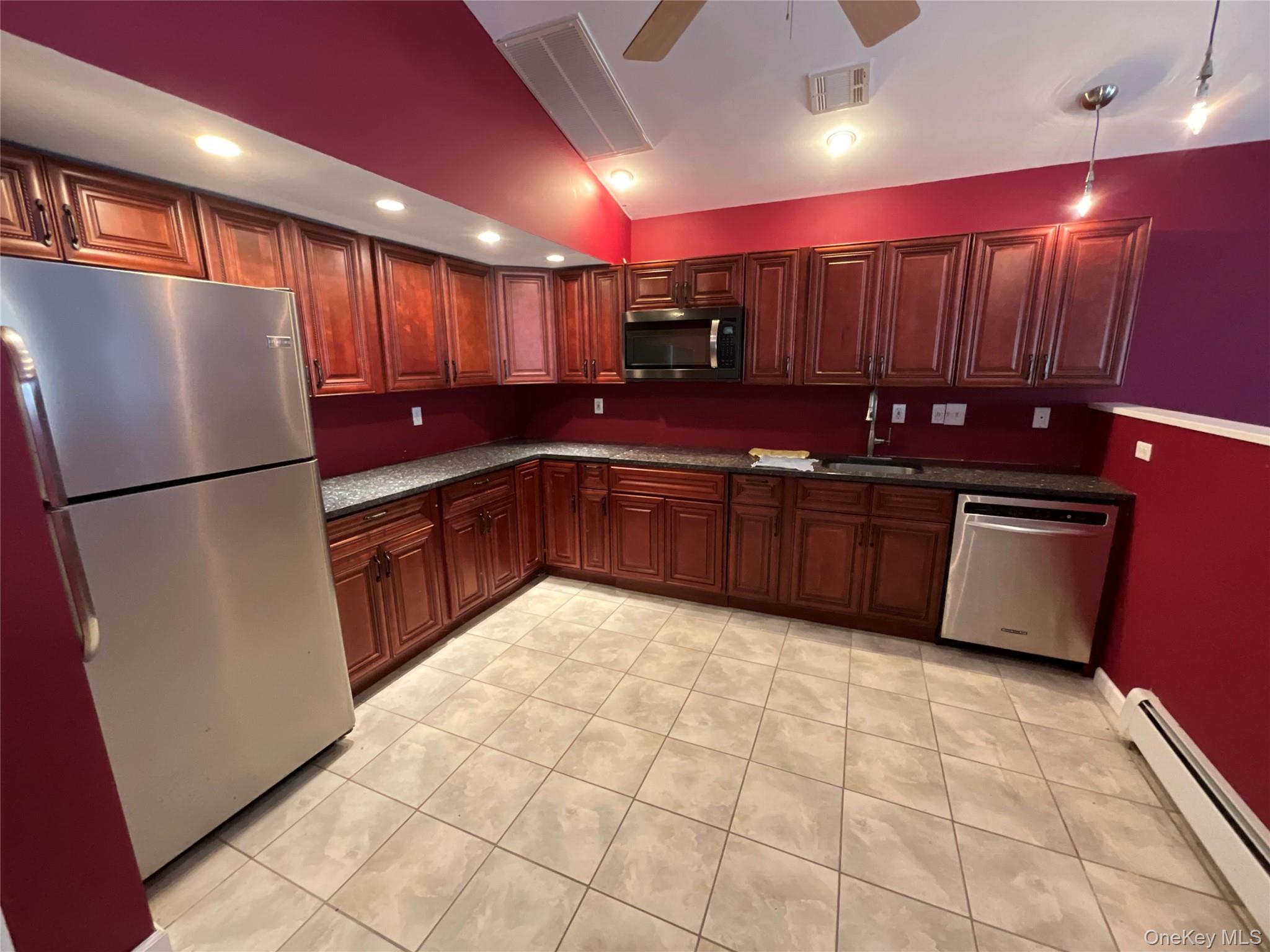 a large kitchen with stainless steel appliances a sink a refrigerator and a microwave