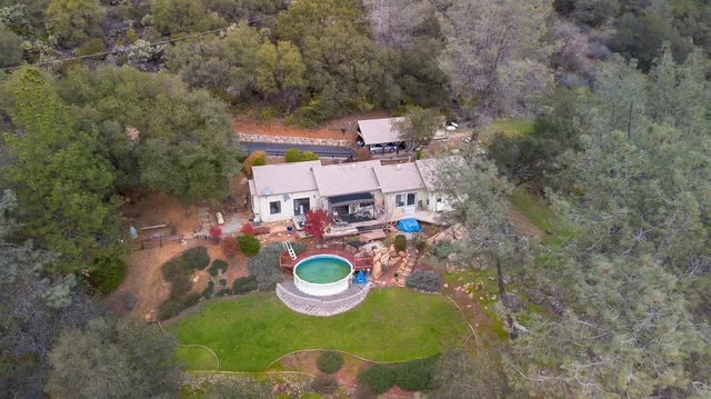 an aerial view of a house with garden space and trees all around