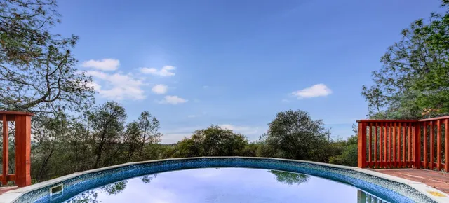 a view of balcony with wooden floor and trees around