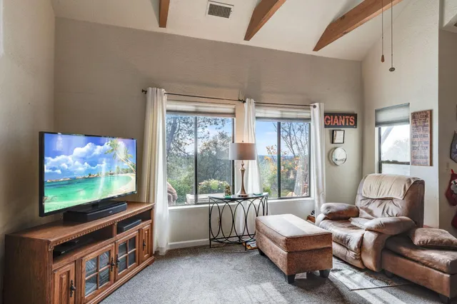 a living room with furniture a flat screen tv and floor to ceiling window