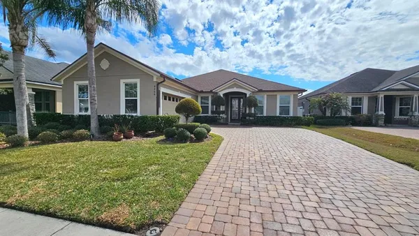 a front view of a house with a yard and potted plants