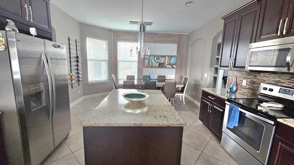 a kitchen with stainless steel appliances kitchen island granite countertop a refrigerator a stove a sink dishwasher and wooden cabinets with wooden floor