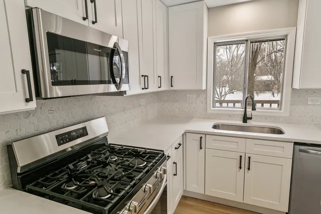a kitchen with white cabinets appliances and window