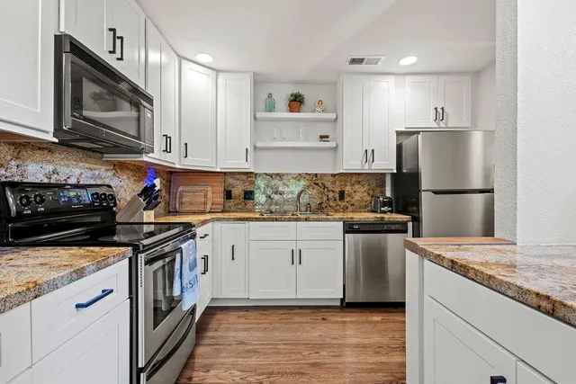 a kitchen with stainless steel appliances granite countertop a refrigerator stove microwave and sink with wooden cabinets