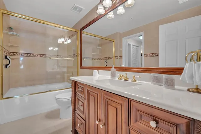 a bathroom with a granite countertop sink a toilet a mirror and shower