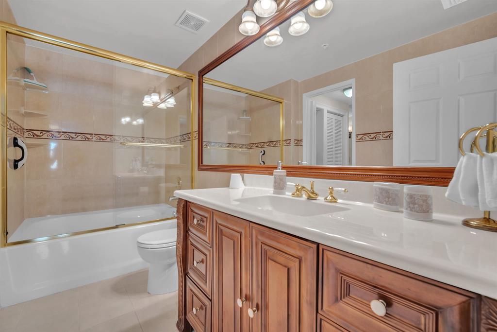 630 South Sapodilla Avenue, Unit 407 West Palm Beach, FL 33401 - Photo 4 of 25 a bathroom with a granite countertop sink a toilet a mirror and shower