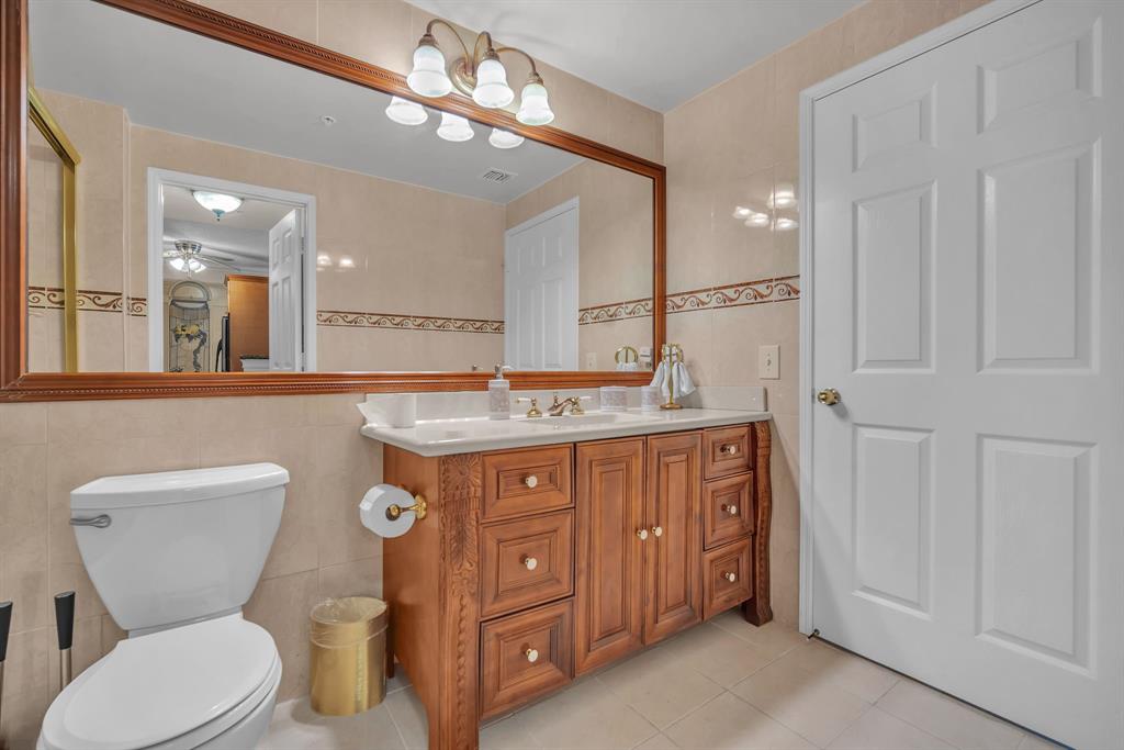 630 South Sapodilla Avenue, Unit 407 West Palm Beach, FL 33401 - Photo 5 of 25 a bathroom with a granite countertop toilet sink and a mirror