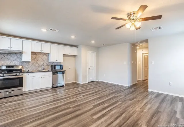 a kitchen with granite countertop a stove cabinets and wooden floor