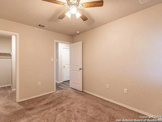 an empty room with a ceiling fan and a window