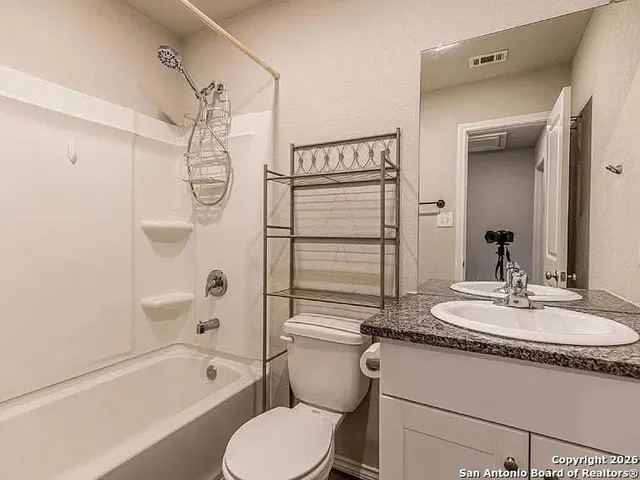 a bathroom with a granite countertop sink toilet mirror and bathtub