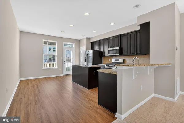 a kitchen with stainless steel appliances granite countertop a stove top oven a sink and a refrigerator