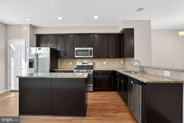 a kitchen with stainless steel appliances granite countertop a stove a sink dishwasher and a refrigerator with wooden cabinets