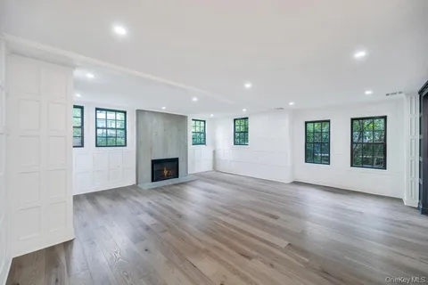 an empty room with wooden floor fireplace and windows