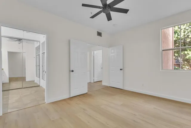 an empty room with a window and a fan