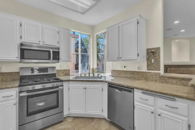 a kitchen with granite countertop white cabinets stainless steel appliances and a sink
