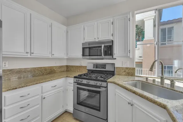a kitchen with granite countertop white cabinets stainless steel appliances and a sink