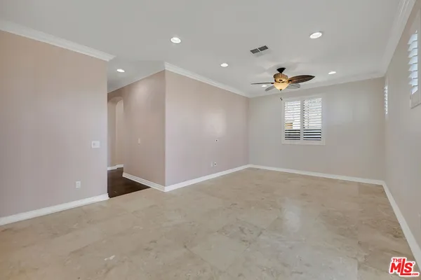 an empty room with wooden floor fan and windows