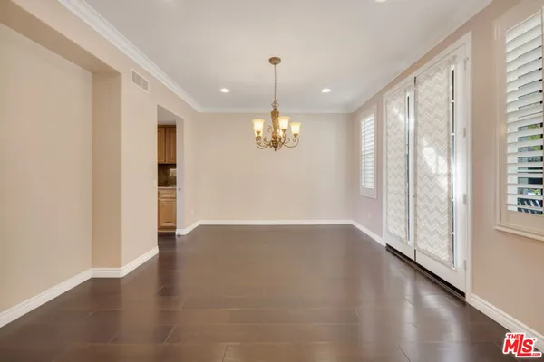 a view of a livingroom with a furniture wooden floor kitchen and windows