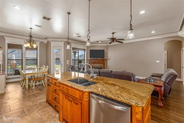 a kitchen with stainless steel appliances granite countertop a sink a stove and a wooden floors