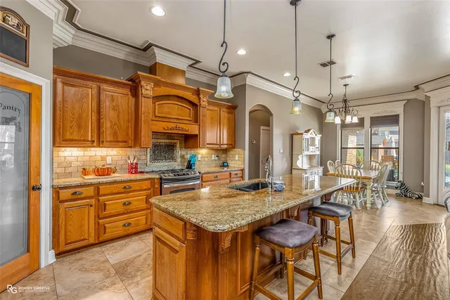 a kitchen that has a kitchen island wooden cabinets and stainless steel appliances