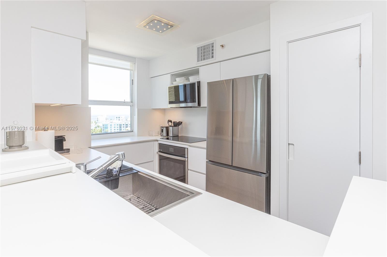 90 Alton Road, Unit 1411 Miami Beach, FL 33139 - Photo 9 of 36 a kitchen with stainless steel appliances a refrigerator and a stove top oven