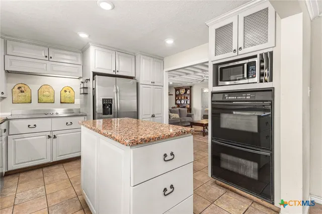 a kitchen with granite countertop cabinets stainless steel appliances and a counter space