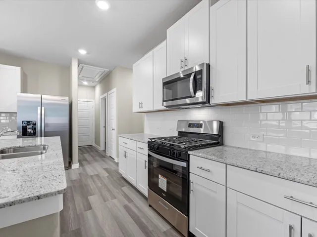 a kitchen with stainless steel appliances granite countertop a stove a sink and a microwave