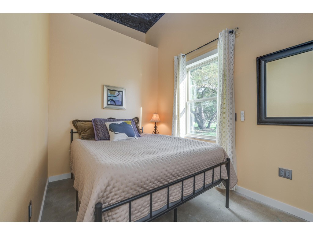 250 Caliche Road Wimberley, TX 78676 - Photo 17 of 40 a bedroom with a bed a window and lamp