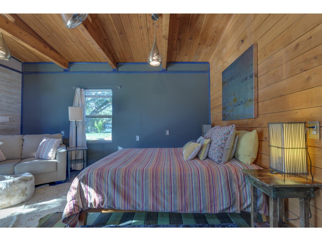 250 Caliche Road Wimberley, TX 78676 - Photo 30 of 40 a bedroom with a bed a couch and dresser