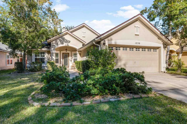 a view of a white house with a big yard and potted plants