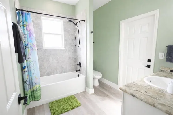 a bathroom with a granite countertop bathtub shower sink and toilet